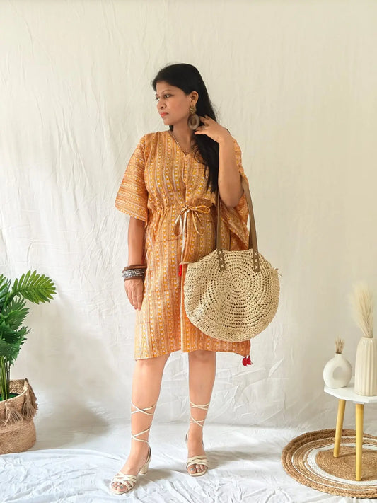 Model in orange Sanganeri block print kaftan with boho bag, wooden earrings, kadas, and strappy heels.