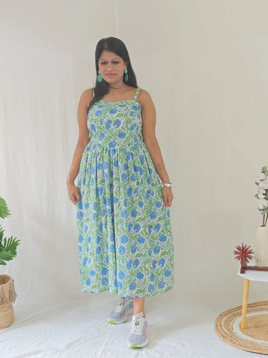 Front view of spaghetti strap floral dress styled casually with white sneakers.