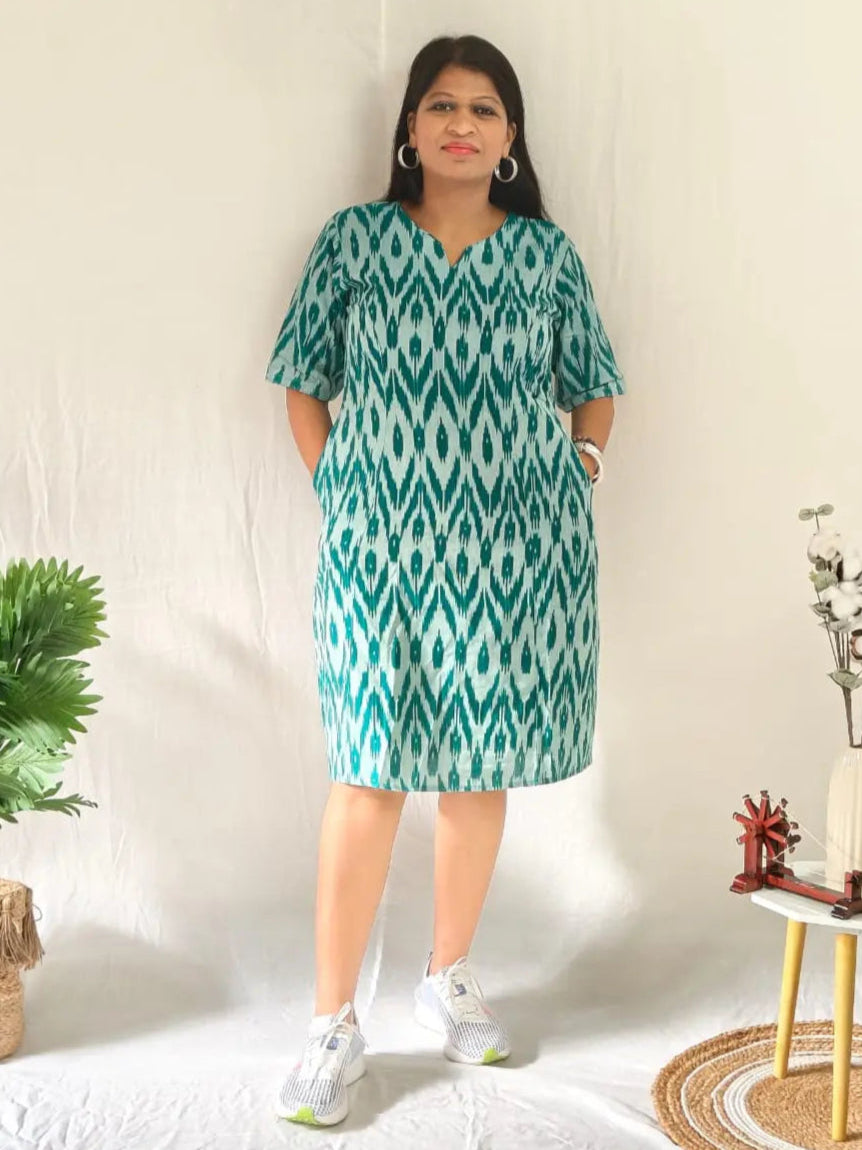 Front view of green ikkat shift dress styled in a casual look with white shoes.
