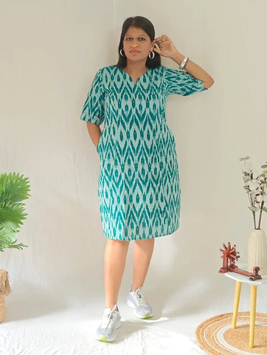 Front view of green ikkat shift dress styled in a casual look with white shoes.