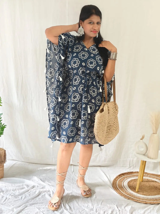 Front view of blue block print kaftan with tassels, styled boho with earrings, tie-up flats, and bag.