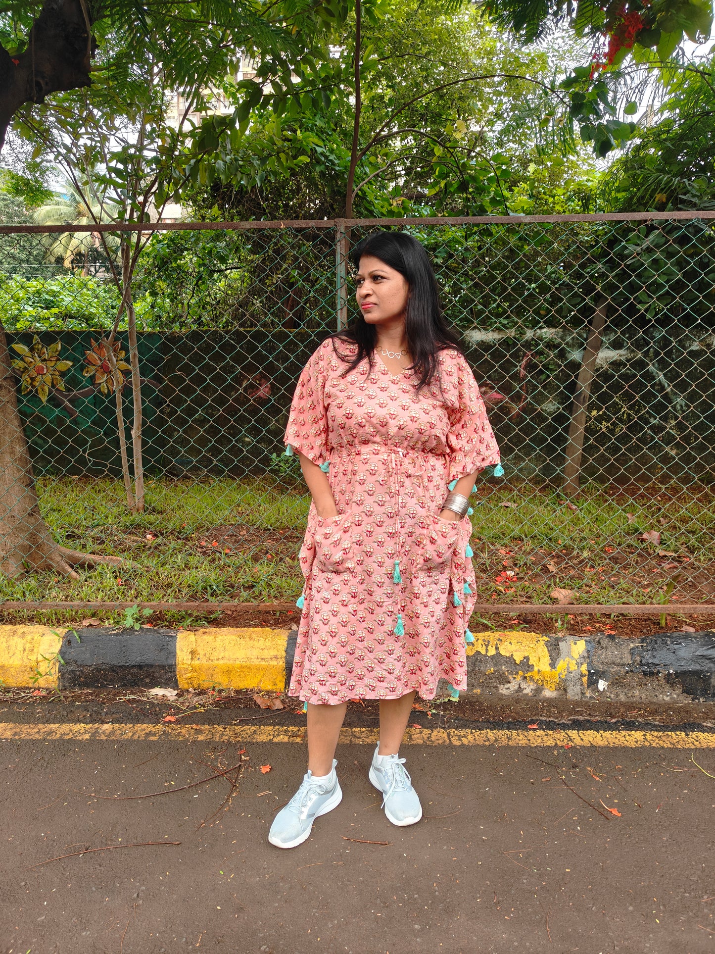 Front view of peach kaftan with tassels, styled in a casual look.