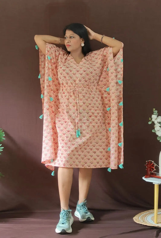 Front view of peach kaftan with tassels, styled in a casual look.