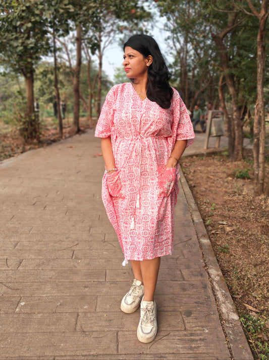 Front view of pink block print kaftan with contrast pocket, styled with casual shoes.