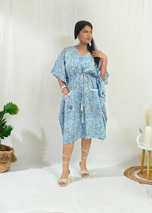 Front view of model wearing a blue kaftan styled in a boho look with tie-up sandals and statement boho earrings.