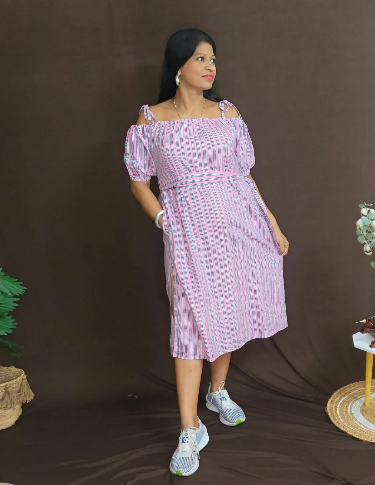 Model wearing pink striped off-shoulder dress with pockets and belt — front profile.