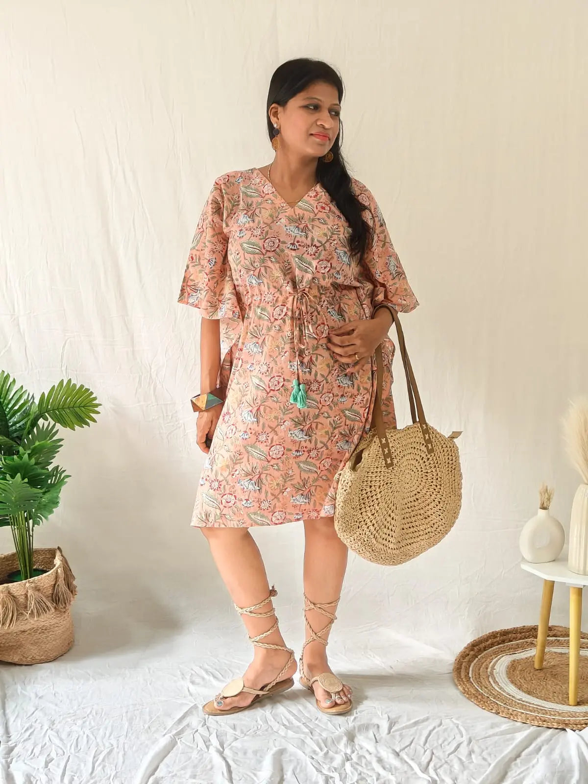 Model in peach Sanganeri cotton kaftan styled with boho accessories, handcrafted bag, and strappy tie-up sandals
