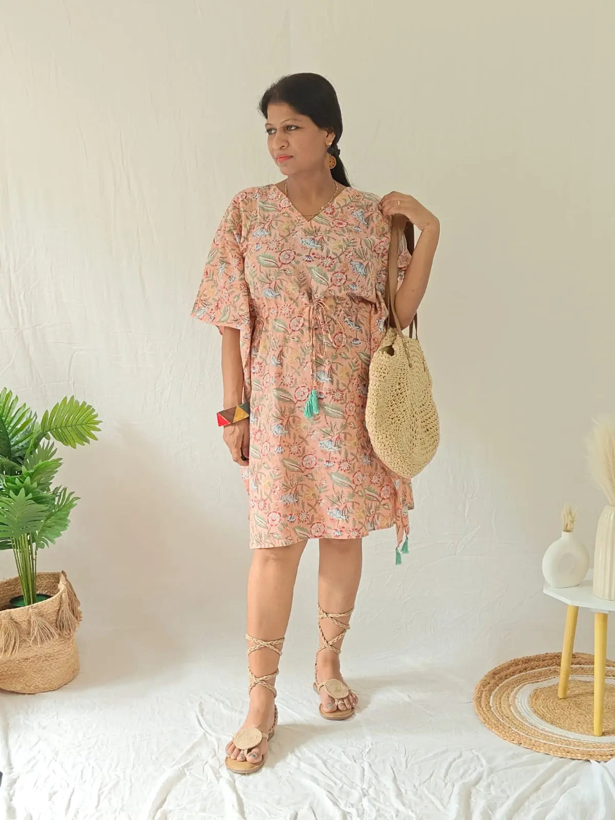Model in peach Sanganeri cotton kaftan styled with boho accessories, handcrafted bag, and strappy tie-up sandals