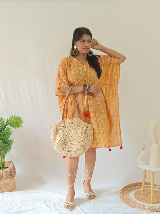 Model in orange Sanganeri block print kaftan with boho bag, wooden earrings, kadas, and strappy heels.