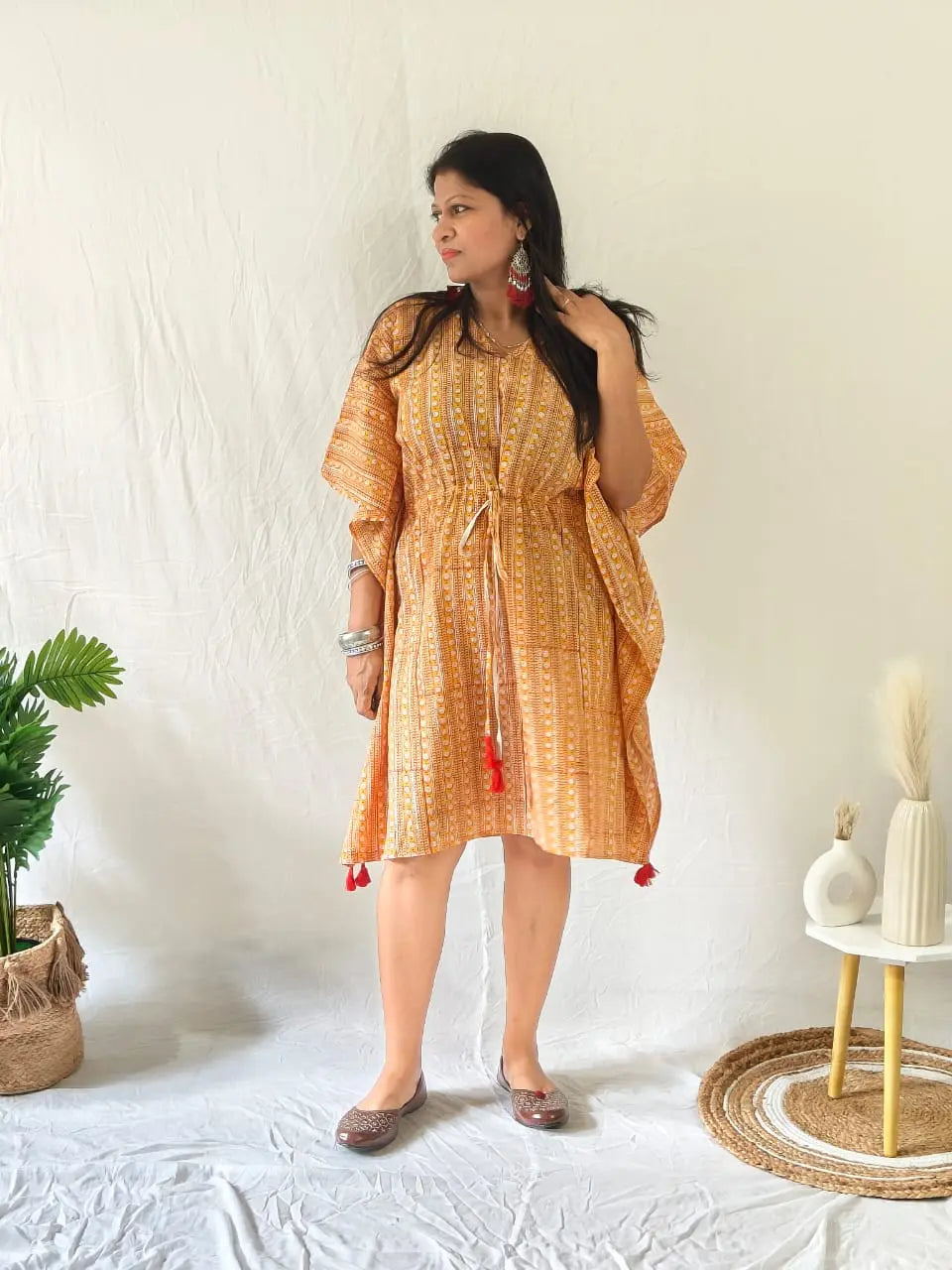 Model in orange Sanganeri kaftan with oxidised earrings, bangles, and juttis for a festive touch.