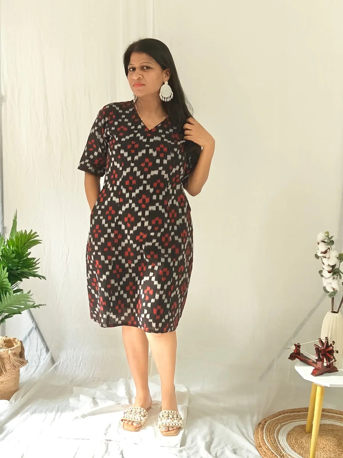 Front view of black ikkat dress with flats and statement earrings.
