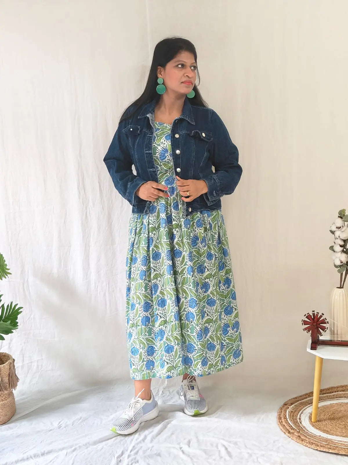 Front view of spaghetti strap floral dress styled with denim jacket and casual shoes.