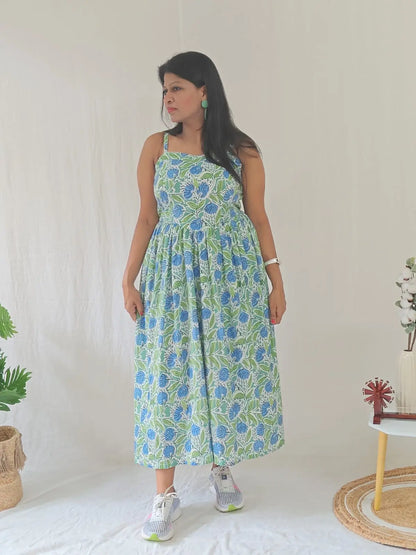 Front view of spaghetti strap floral dress styled casually with white sneakers.