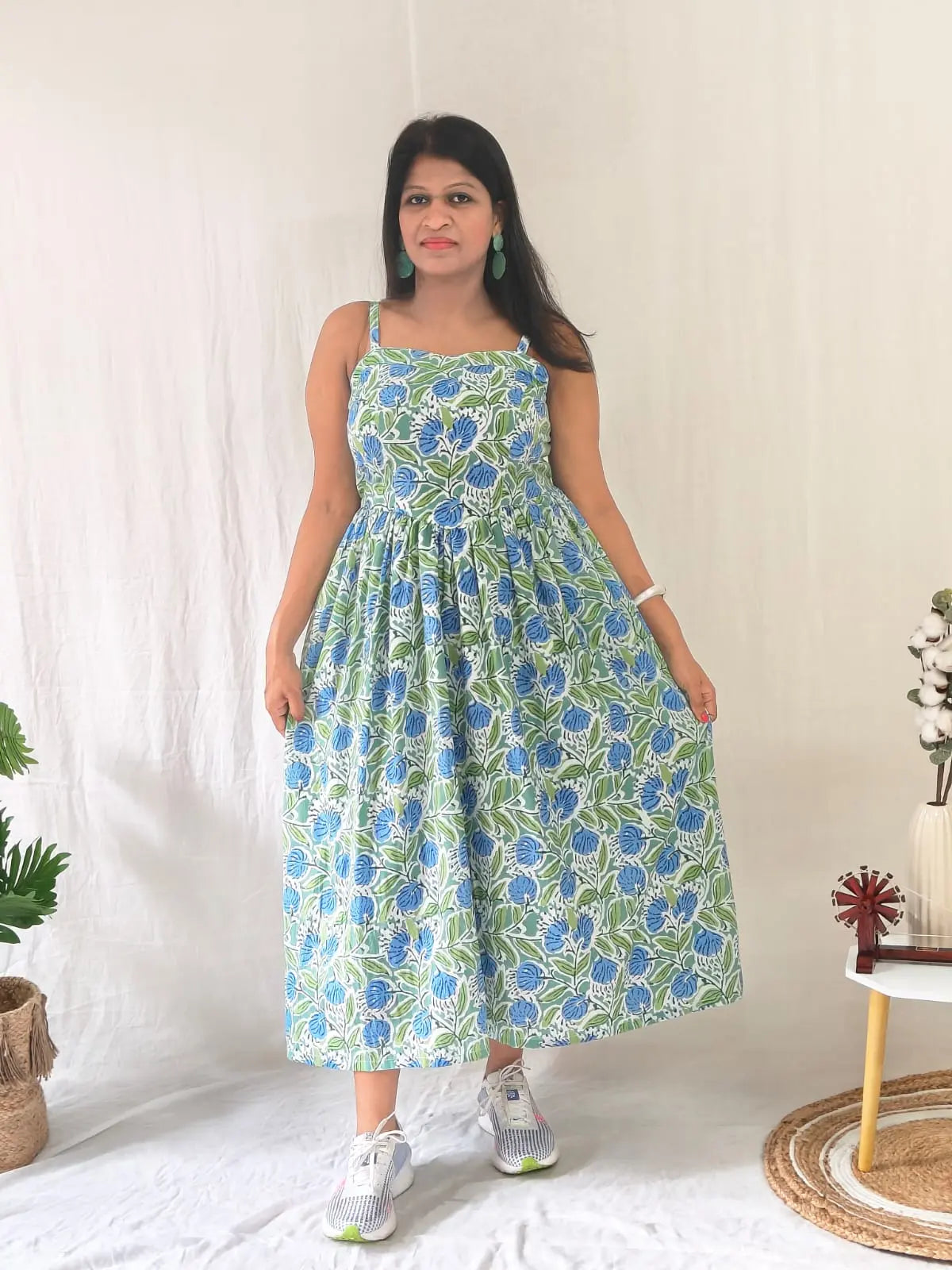 Front view of spaghetti strap floral dress styled casually with white sneakers.