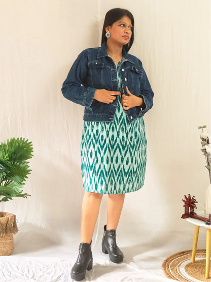 Front view of green ikkat shift dress layered with jacket and styled with ankle boots.