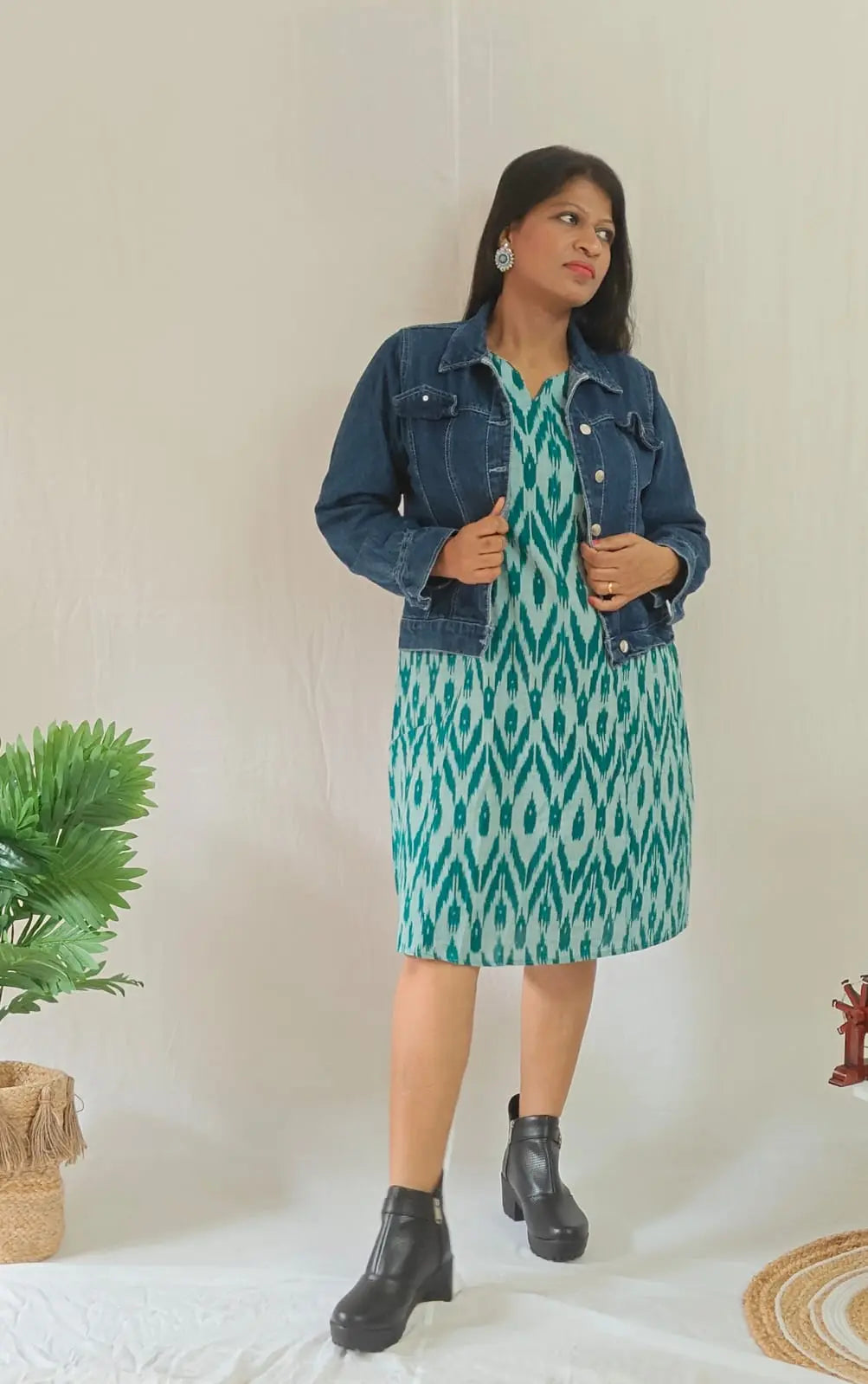 Front view of green ikkat shift dress layered with jacket and styled with ankle boots.