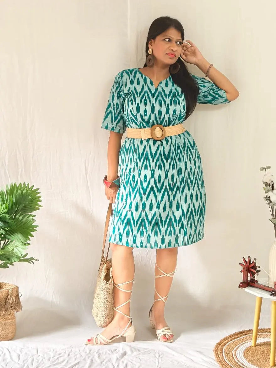 Boho look in green ikkat shift dress with belt, tie-up sandals, and bag.