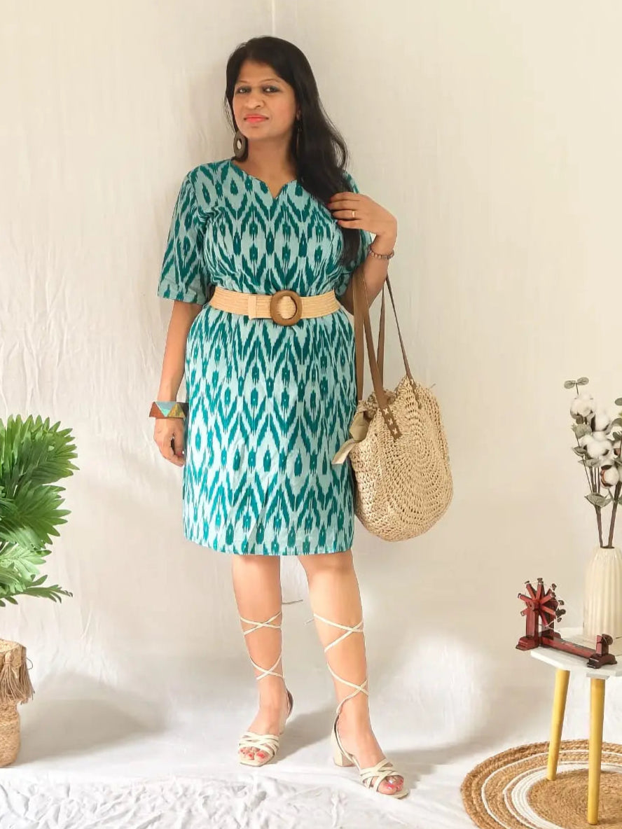 Boho look in green ikkat shift dress with belt, tie-up sandals, and bag.