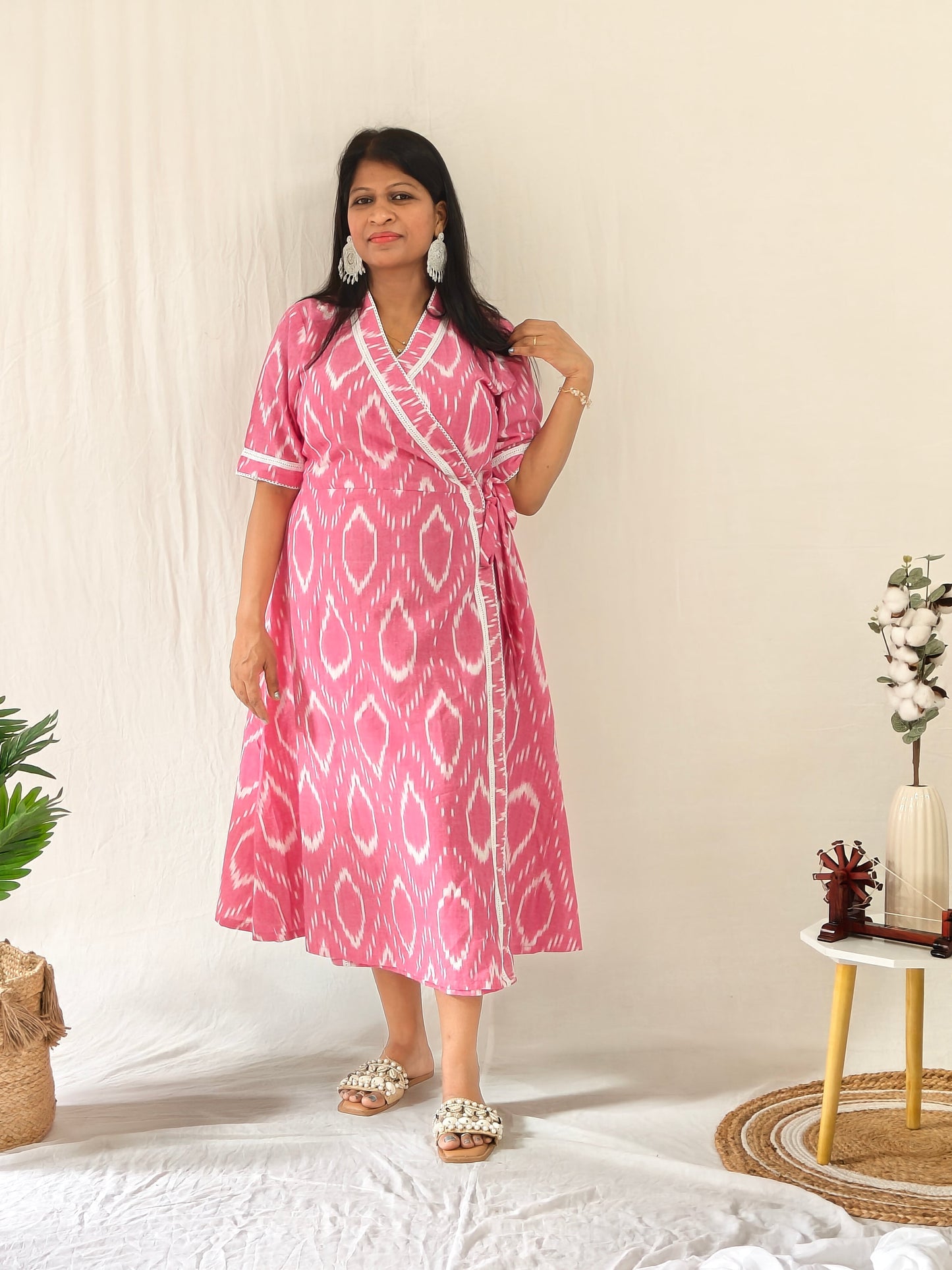 Model in a Pink Ikat dress paired with shell-embellished sandals and boho-style earrings for a relaxed, artistic look.