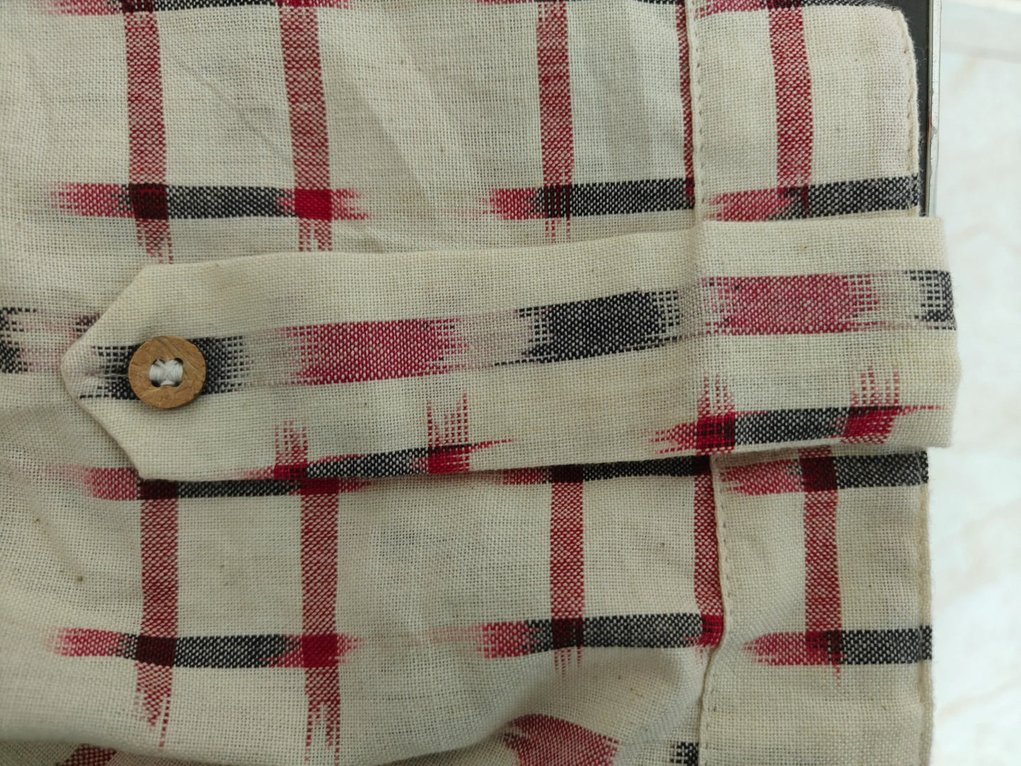 Zoom view of sleeve with decorative tab and button detail on cuff.