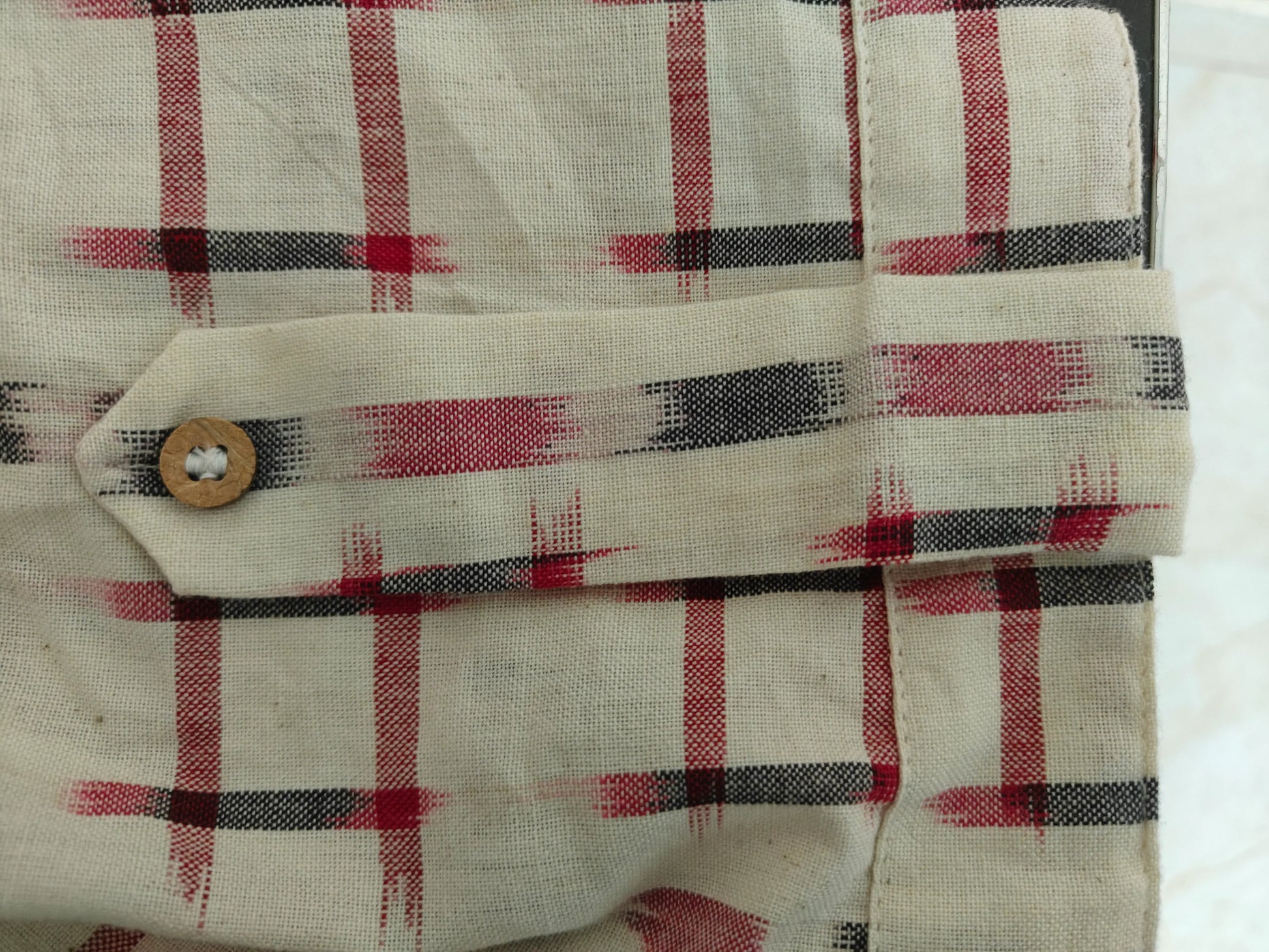 Zoom view of sleeve with decorative tab and button detail on cuff.