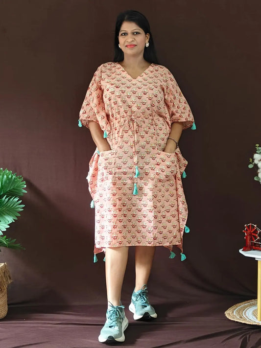 Front view of peach kaftan with tassels, styled in a casual look.