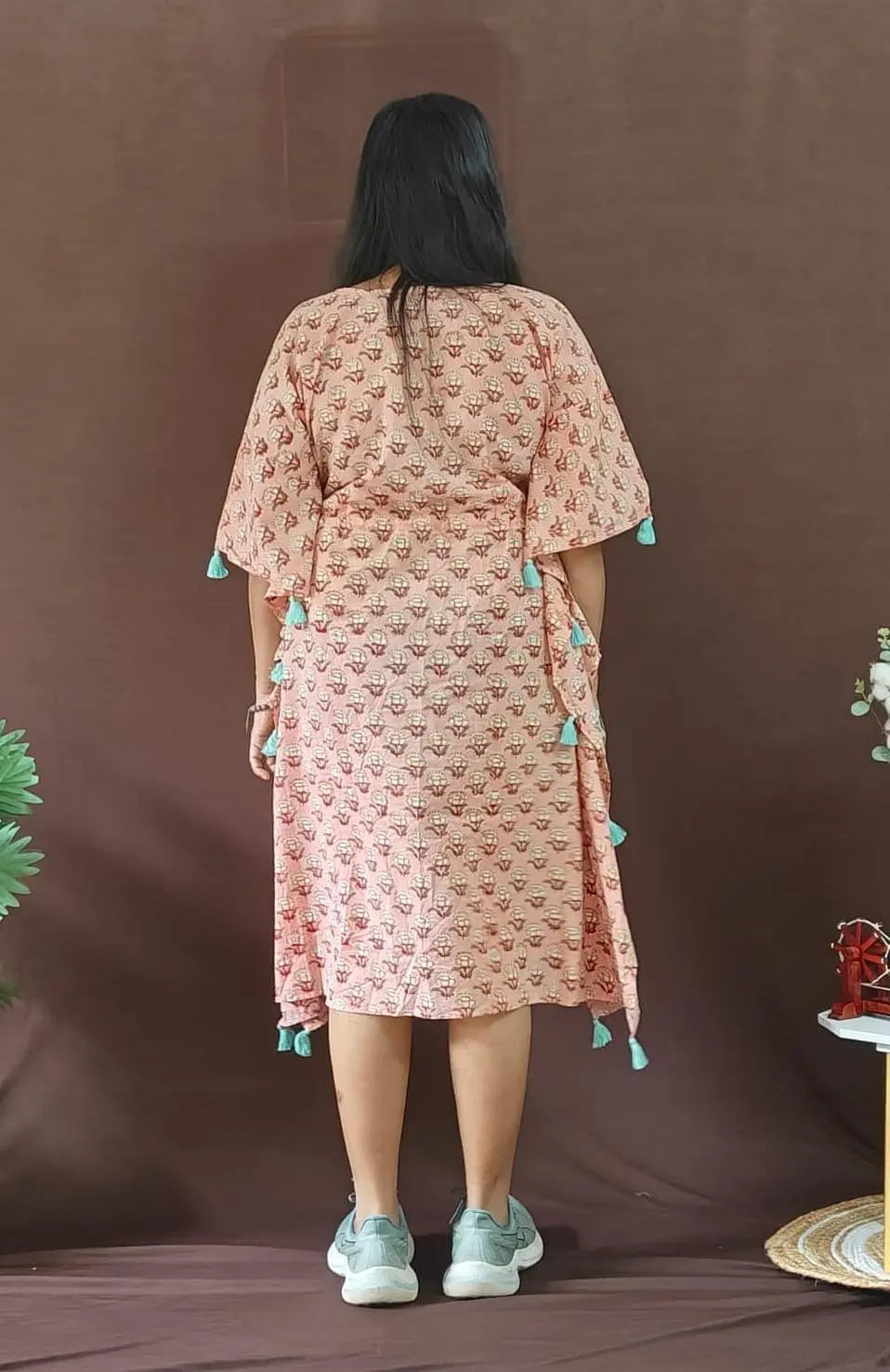 Back view of peach kaftan with tassels.







