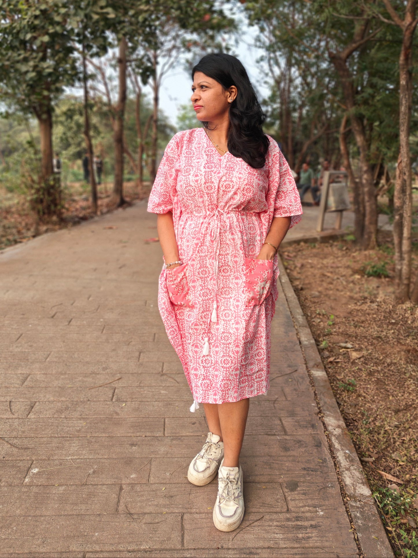Front view of pink block print kaftan with contrast pocket, styled with casual shoes.