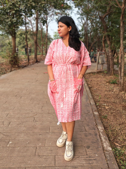 Front view of pink block print kaftan with contrast pocket, styled with casual shoes.