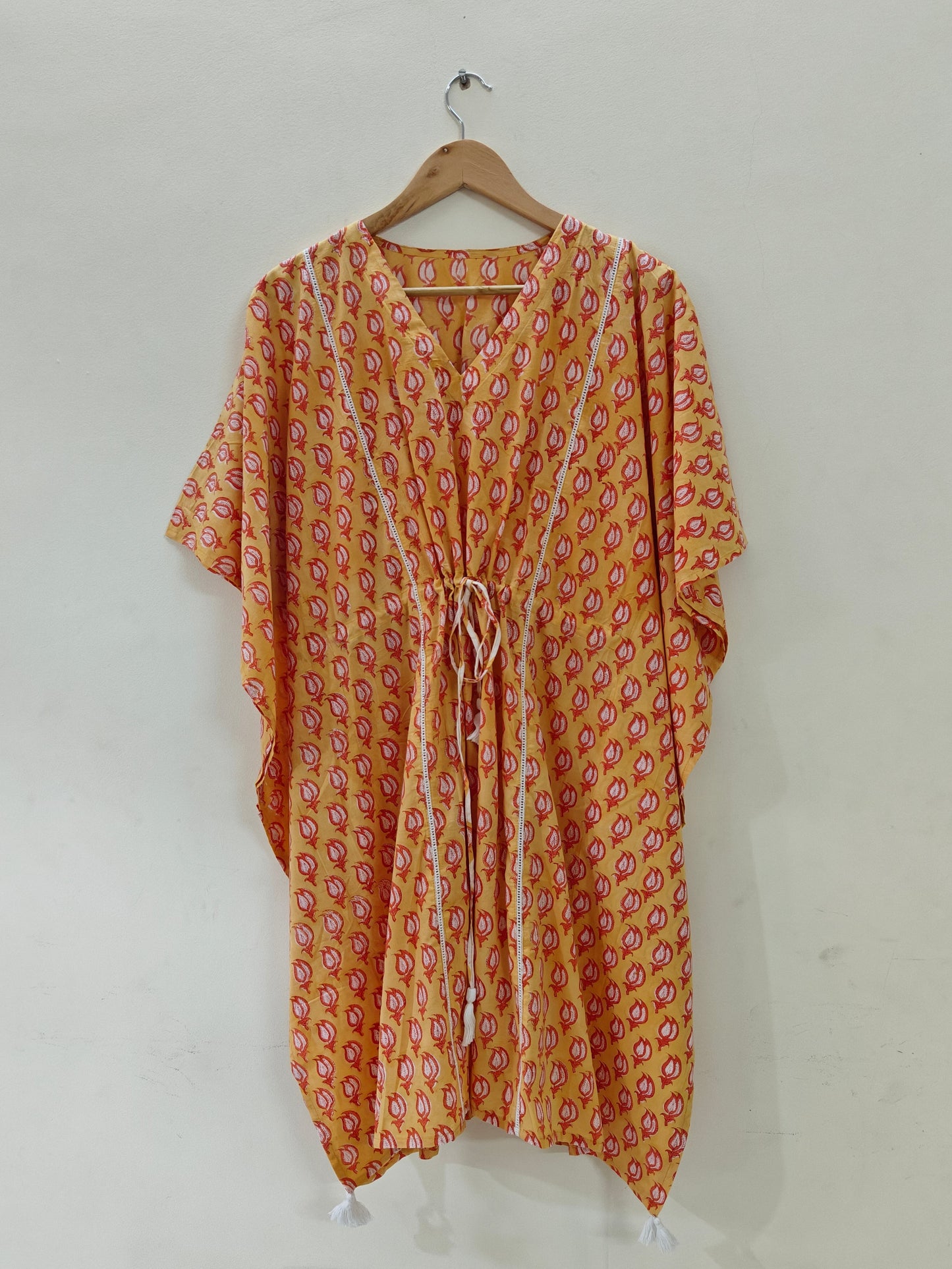 Orange kaftan hanging on hanger, front view.