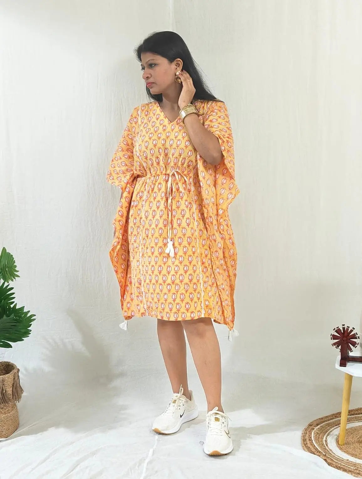 Front view of orange kaftan with casual shoes.